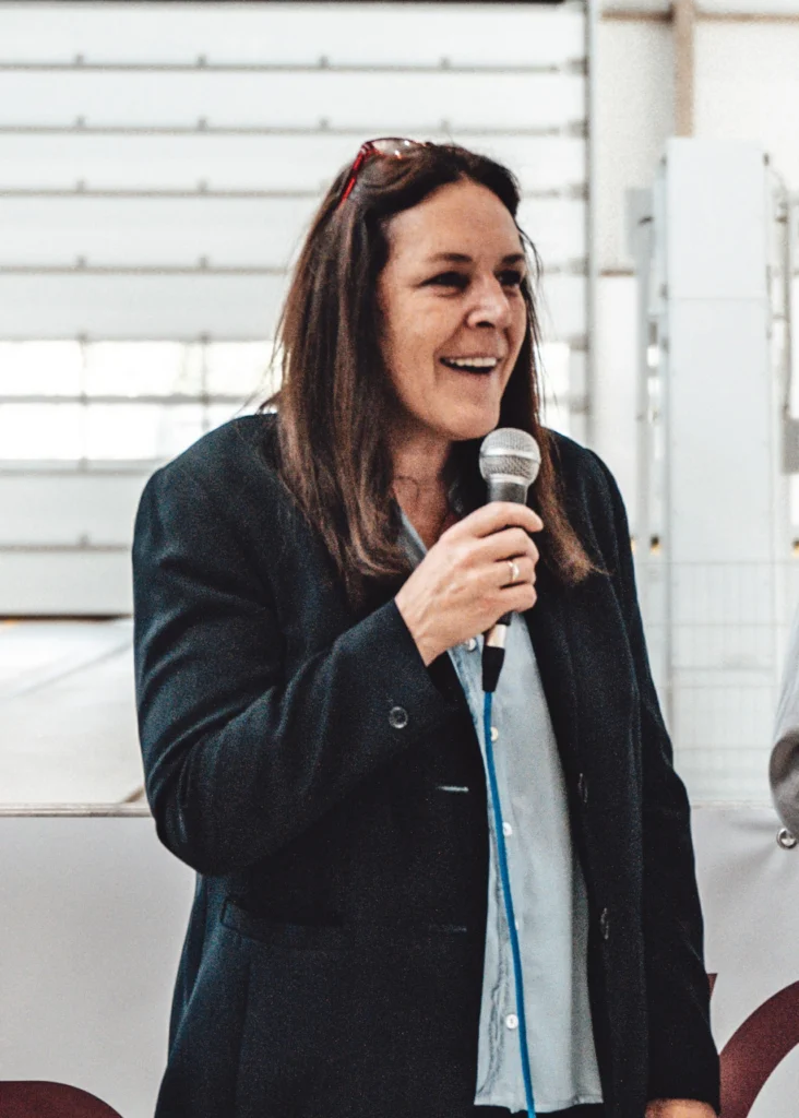 Patrizia Langer hält ein Mikrofon und spricht bei einer Veranstaltung von Adesso Rail